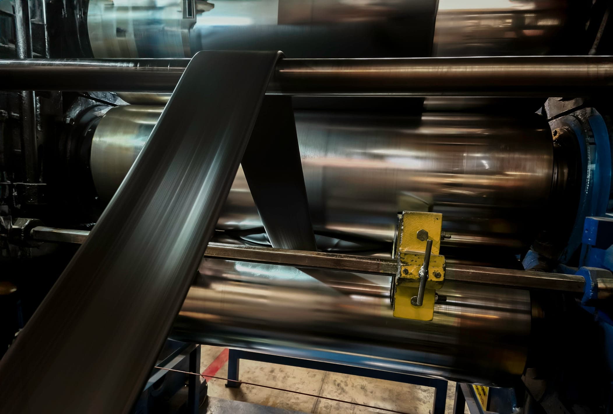 automated industrial production system operating around a large precision roller assembly, illustrating how manufacturing automation and inline inspection systems rely on stable mechanical conditions for accurate process control and measurement consistency