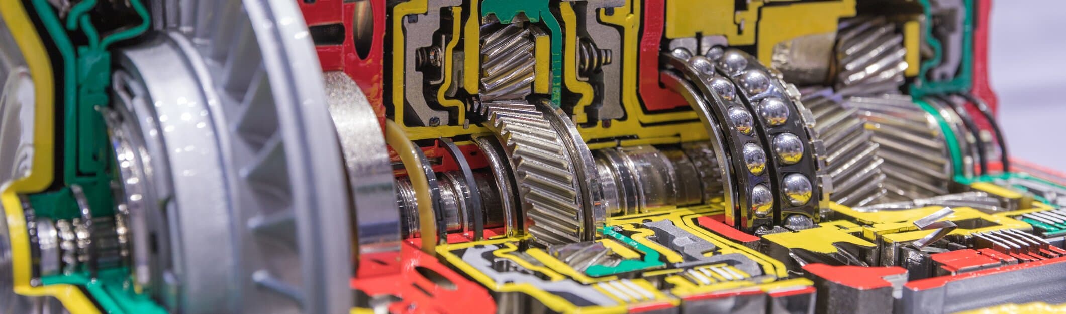 cutaway view of an automotive transmission showing interlocking helical gears, shafts, and bearings inside the gearbox housing