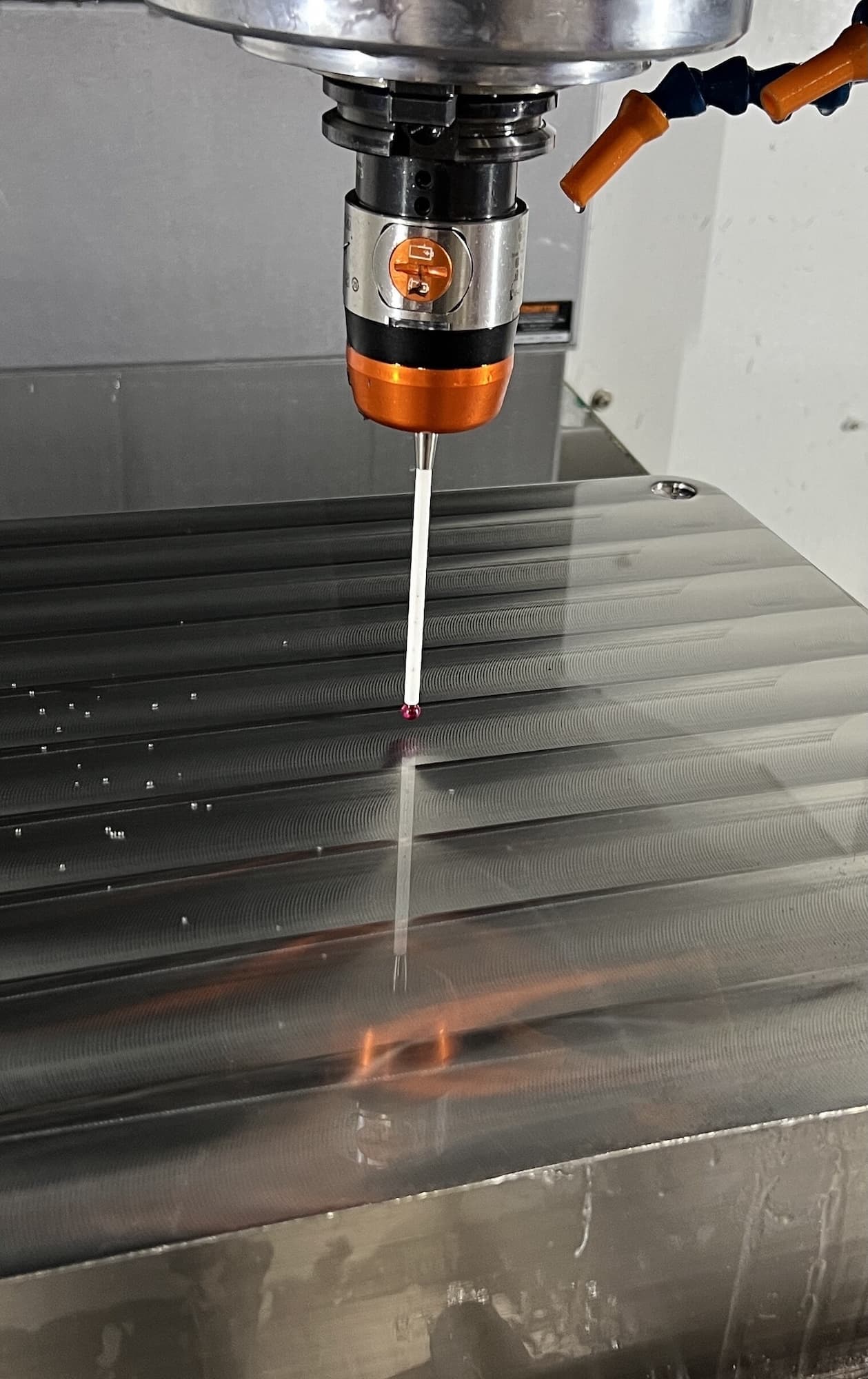 precision probe measures the surface of a machined metal build plate during inspection in a manufacturing facility.