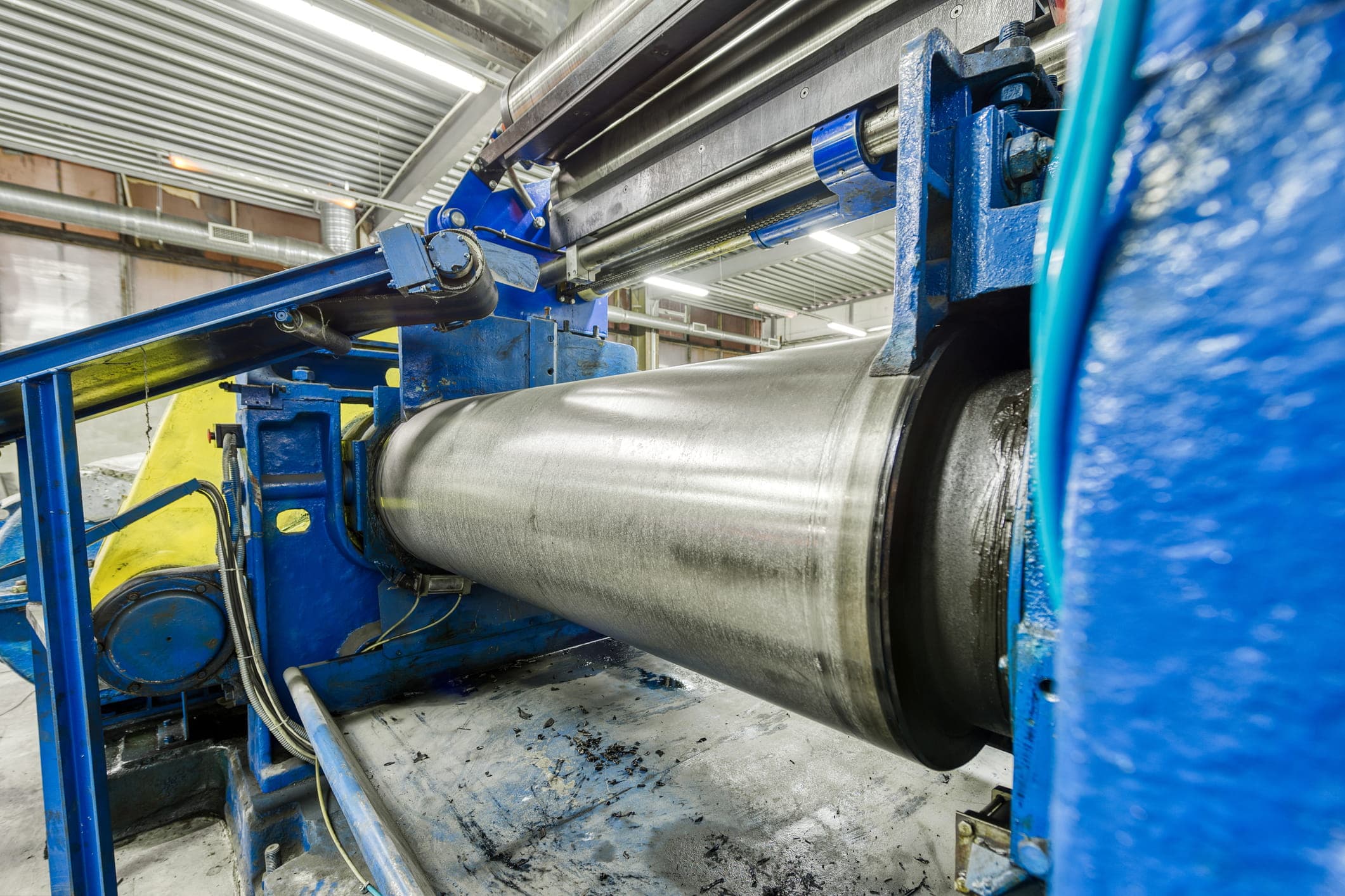 industrial maintenance technician inspecting large precision rollers inside a cardboard manufacturing machine, representing how machining accuracy, concentricity, and surface finish affect equipment stability and long-term production performance after repair cycles